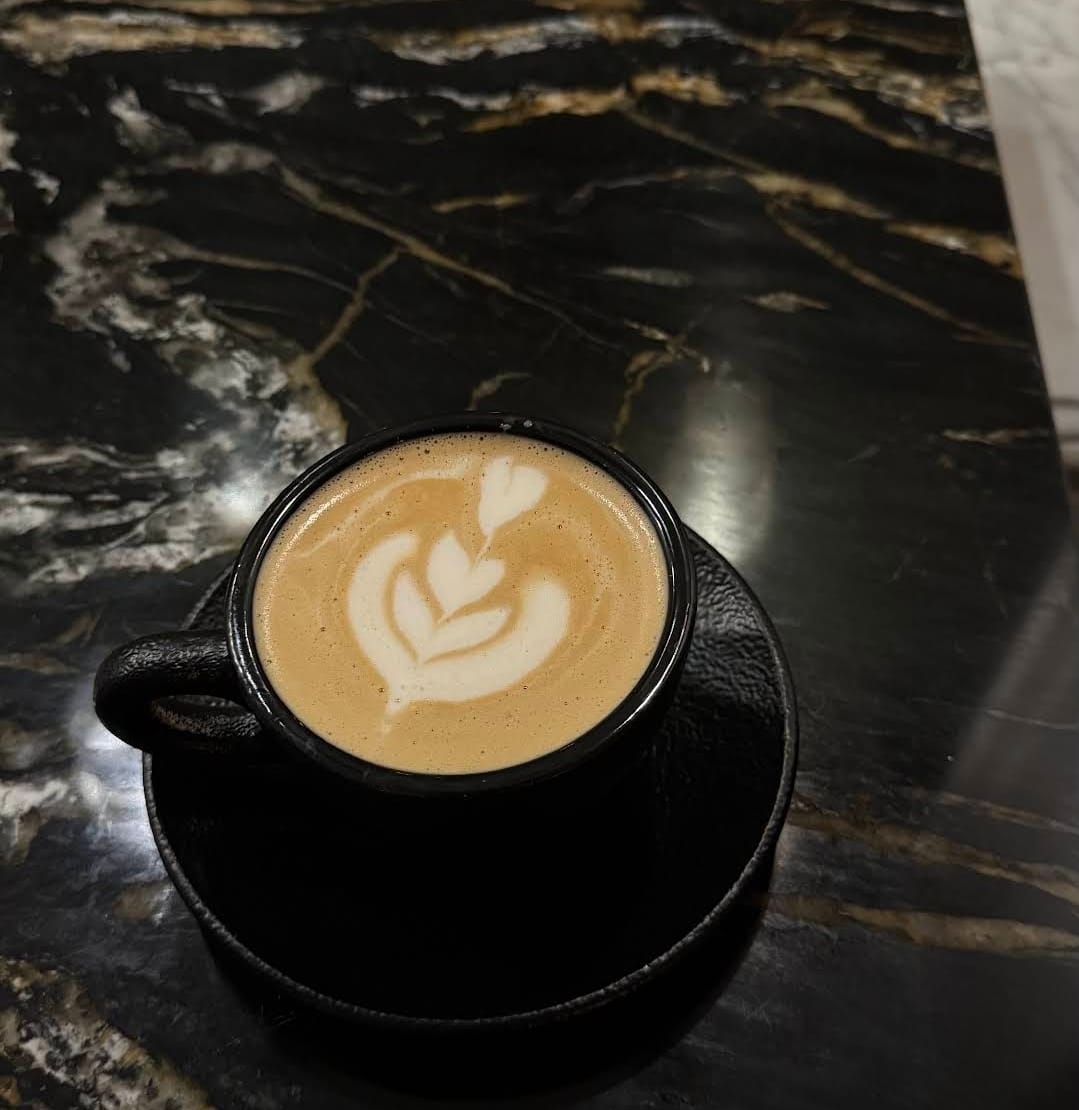 Cappuccino mit Latte Art in schwarzer Tasse